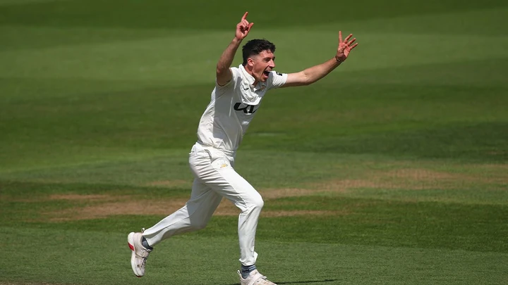 A Surrey seam bowler in whites, arms raised, appealing for a wicket at the Kia Oval