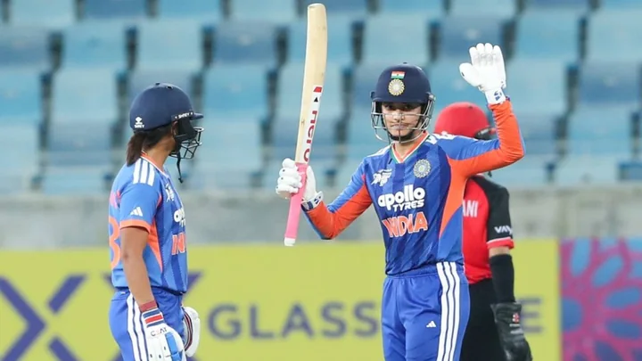 Smriti Mandhana in India blue raises her bat to acknowledge her century against Hong Kong